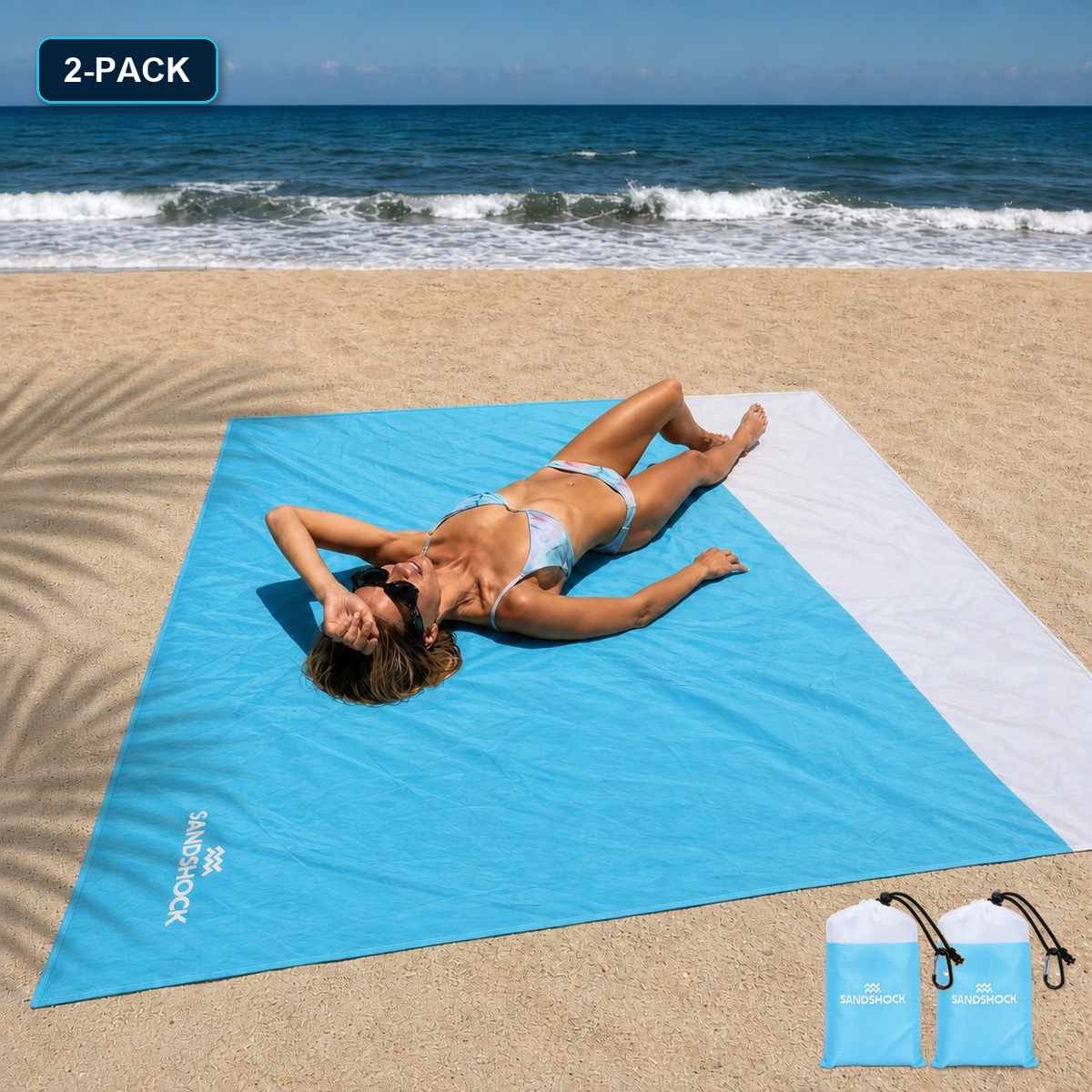 Woman relaxing on a turquoise Sandshock sandproof beach blanket with two carry bags